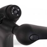Close-up of a black prosthetic arm with a thumbstick and a set of four arrow buttons for control, featuring textured surfaces and ergonomic design.