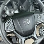 Close-up of a Honda car steering wheel equipped with various adaptive driving controls and buttons, designed for accessibility to assist drivers with limited hand mobility.
