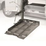 A metal wheelchair lift extended from the side of a van, with a textured platform and safety rails, designed to assist individuals in entering or exiting the vehicle.