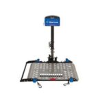 A metal wheelchair lift platform with a vertical support post and control box, designed for vehicle access. The platform has slots and safety rails on the sides.