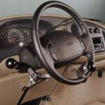 A car steering wheel equipped with hand controls designed for drivers with disabilities, including levers and knobs attached to the wheel and dashboard for easier vehicle operation.