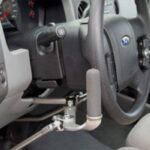 Close-up of a car’s steering wheel with a hand control device installed for accessible driving, showing the lever system near the wheel and dashboard.