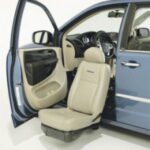 A blue car with the driver-side door open, showing a beige seat that swivels and extends outside the vehicle for easier access.
