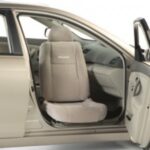 A beige car with the front passenger door open, showing a light-colored seat that swivels outward, designed to help passengers enter and exit the vehicle more easily.