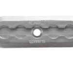 Rectangular metal connector plate with rounded ends, a central circular hole, and four smaller oval slots arranged in pairs on each side. The plate has embossed markings and a grooved surface.
