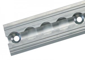 Close-up of a silver metal linear rail with evenly spaced circular indentations and two screw holes at each end, used for guiding mechanical motion in machinery or automation systems.