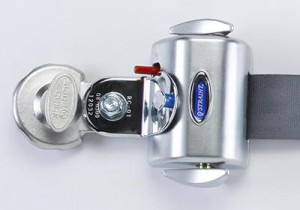 Close-up of a silver seat belt locking device attached to a seat belt strap, with a metallic latch and a visible brand logo reading “OPTILINK.”.
